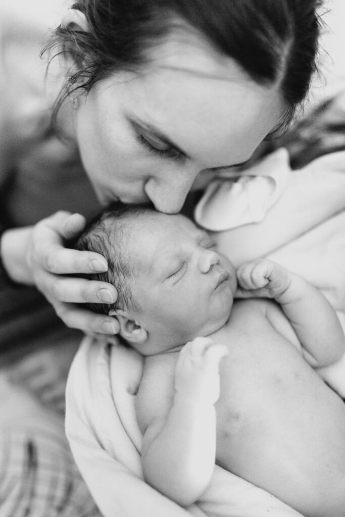 une mère qui embrasse son bébé après son accouchement durant une séance photo nouveau-né en maison de naissance prestations photographe nancy metz